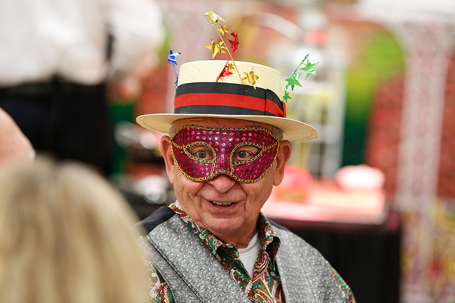 an older gentleman wears a Mardi Gras mask